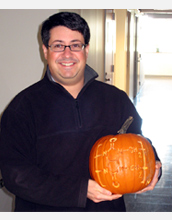 Photo of Lyle Isaacs holding a pumpkin with the chemical structure of the CB[n] molecule.