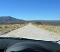 View through fron window of vehicle showing unpaved gravel road in Namibia.