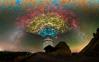 Slice of 3D map of galaxies collected in the first year of Dark Energy Spectroscopic Instrument Survey appears in rainbow of color above NSF Nicholas U. Mayall 4-meter Telescope