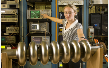 Photo of Laura Saxton testing a multi-cell superconducting radio frequency cavity prototype.