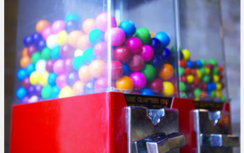 Photo of gumballs of different sizes in a gumball machine.