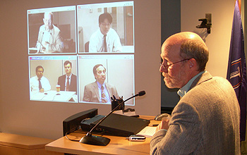 Photo of host in studio and four people on a screen