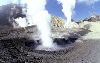 A circular pond containing boiling black mud