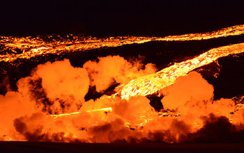 Nighttime glow and steam from a wide lava channel