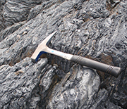 Sedimentary rocks with hammer lying on top.