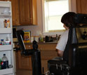 Photo of a disabled person piloting a robotic mobility and manipulation system to open frig door.