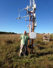 Scientist standing next to cosmic-ray soil moisture sensor