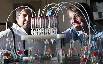 Female and male researchers in a lab with tubes and beakers