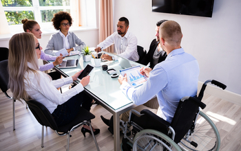 Group including women, minorities, and persons with disabilities work at a table.