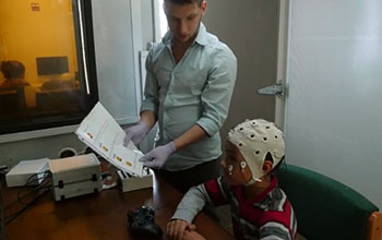 Researcher and youngster with brain monitoring cap