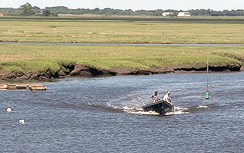 Two people in small boat, water and marsh land