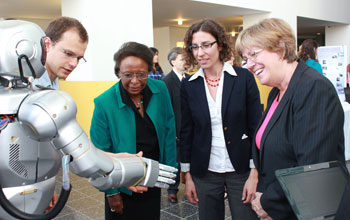 Photo of Cora Marrett, Dahlia Sokolov and Joan Ferrini-Mundy interact with humanoid robot.