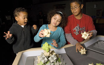 Photo of three children playing with 3-D molecular shapes.