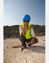 Examining a rock found at a newly discovered site containing dinosaur tracks