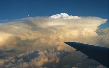 Photo of a plane wing in the foreground and clouds in the background.