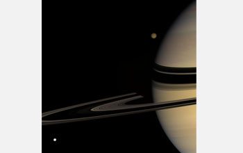 Titan at the top emerging from behind Saturn and Tethys at the bottom left.