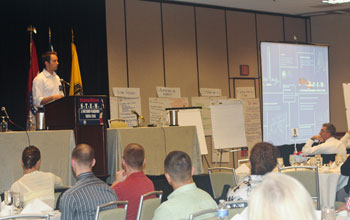 Photo of Kyle Hausmann-Stokes giving a Keynote Address.