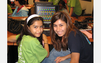 Photo of a student demonstrating a computer game she developed to another student.