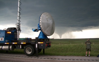 Scientist with Vortex-2 equipment on the side of the road looking at a twister