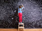 a little girl doing math problems on a black board