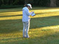 a lady standing in the grass writing in a book