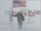 Photo of man at South Pole holding onto U.S. flag in high wind